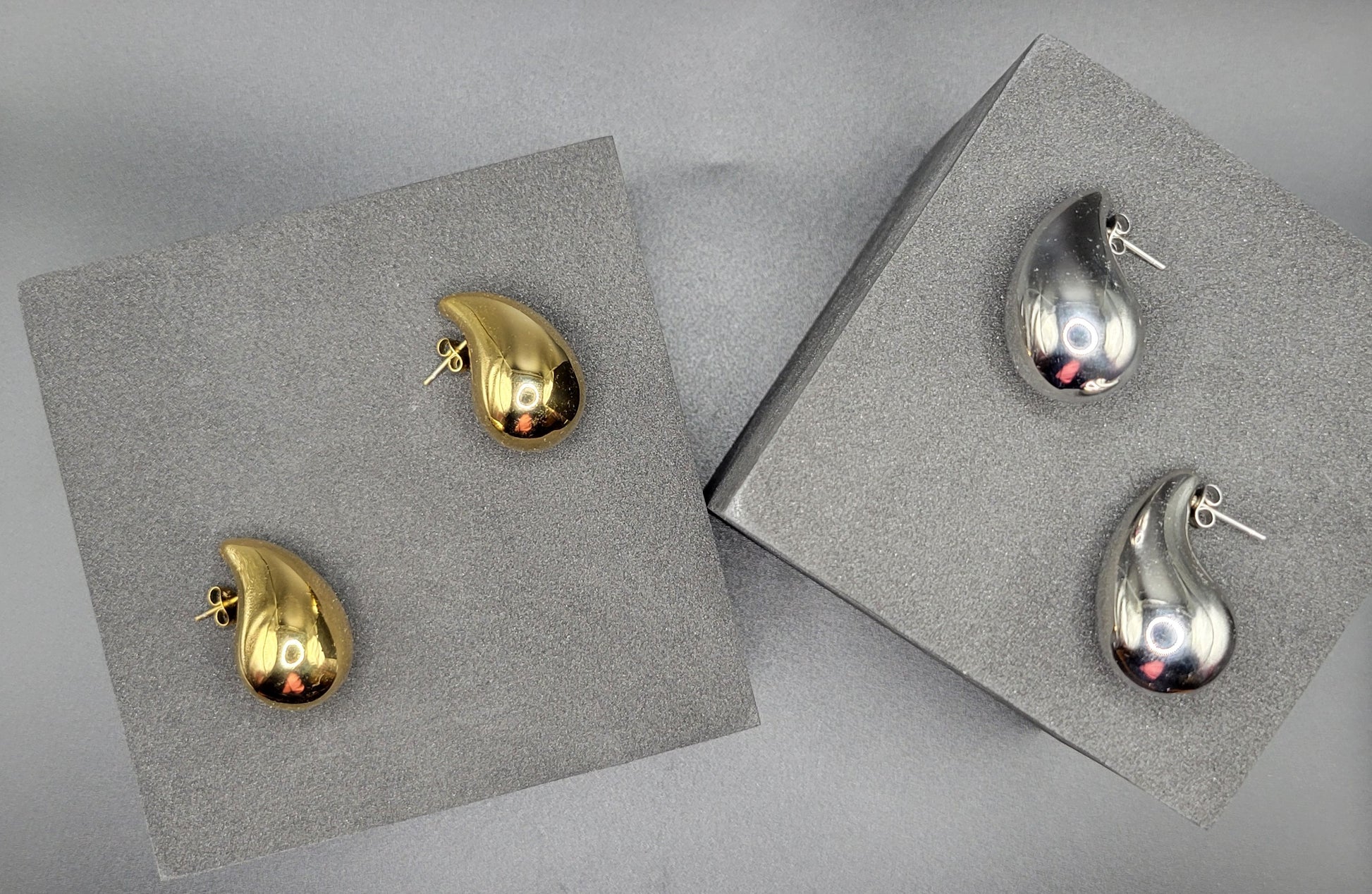 Raindrop-shaped earrings in two colors, gold on the left and silver on the right,