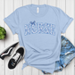 Light blue t-shirt with 'NURSE' printed on it, paired with denim shorts and sneakers on a wooden surface.