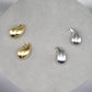 A pair of raindrop-shaped earrings in two colors, gold on the left and silver on the right.