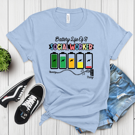 A light blue t-shirt with a graphic that shows battery icons ranging from fully charged to drained, with days of the week labeled underneath each battery level. The text reads 'Battery Life of a Social Worker.
