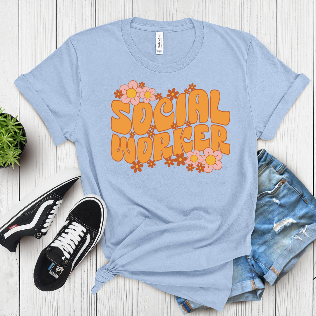 Light blue t-shirt with 'Social Worker' text and flowers on a wooden surface with sneakers and shorts.